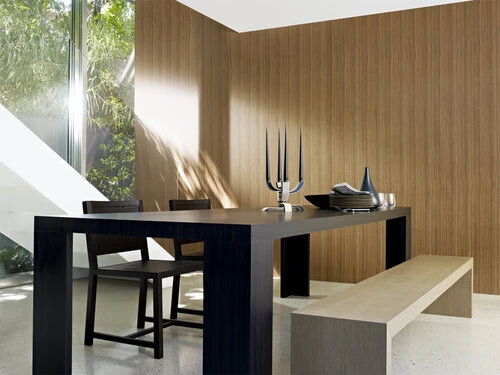 Modern dining room interior with wood paneled walls, contemporary table and chairs, bench, and view to outdoor greenery through a large window.
