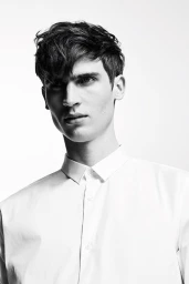 Close-up portrait of a young man wearing a white collared shirt against a plain white background.