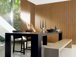 Modern wooden dining table with chairs and bench in a brightly lit interior space with vertical wood panelling.