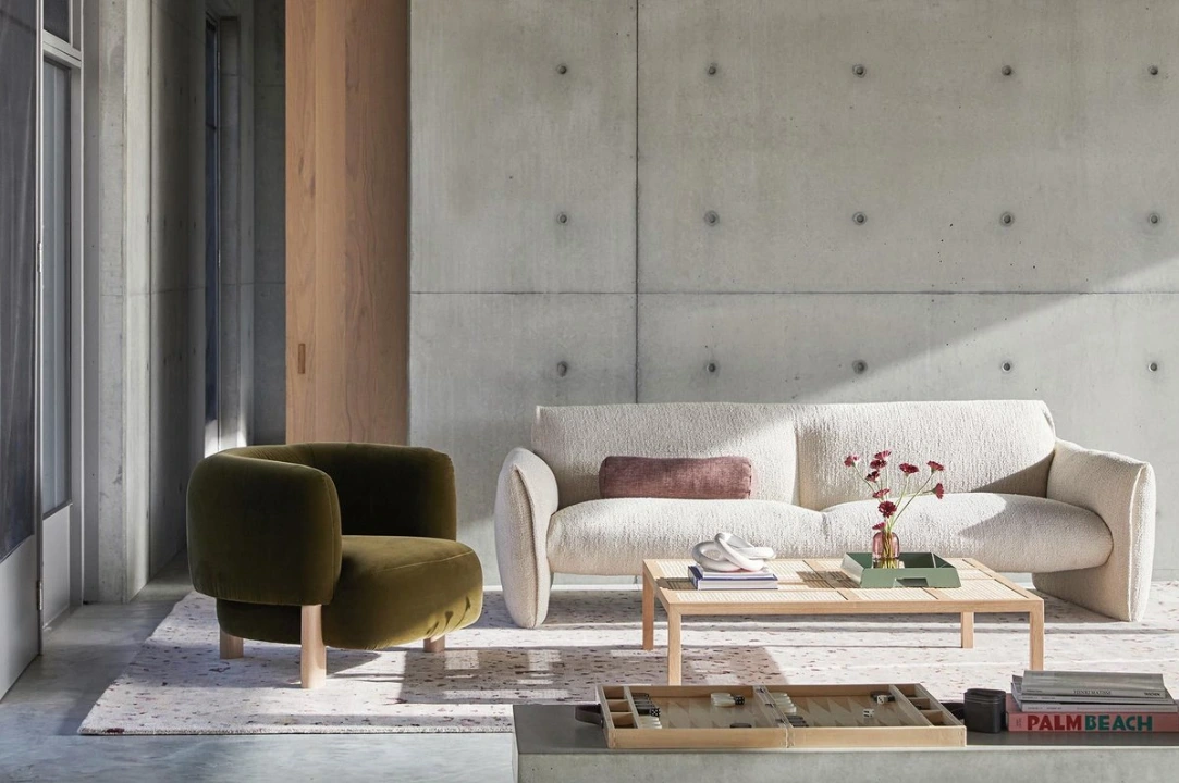 Modern living room interior with an olive green armchair, cream textured sofa, and concrete wall by James Geer