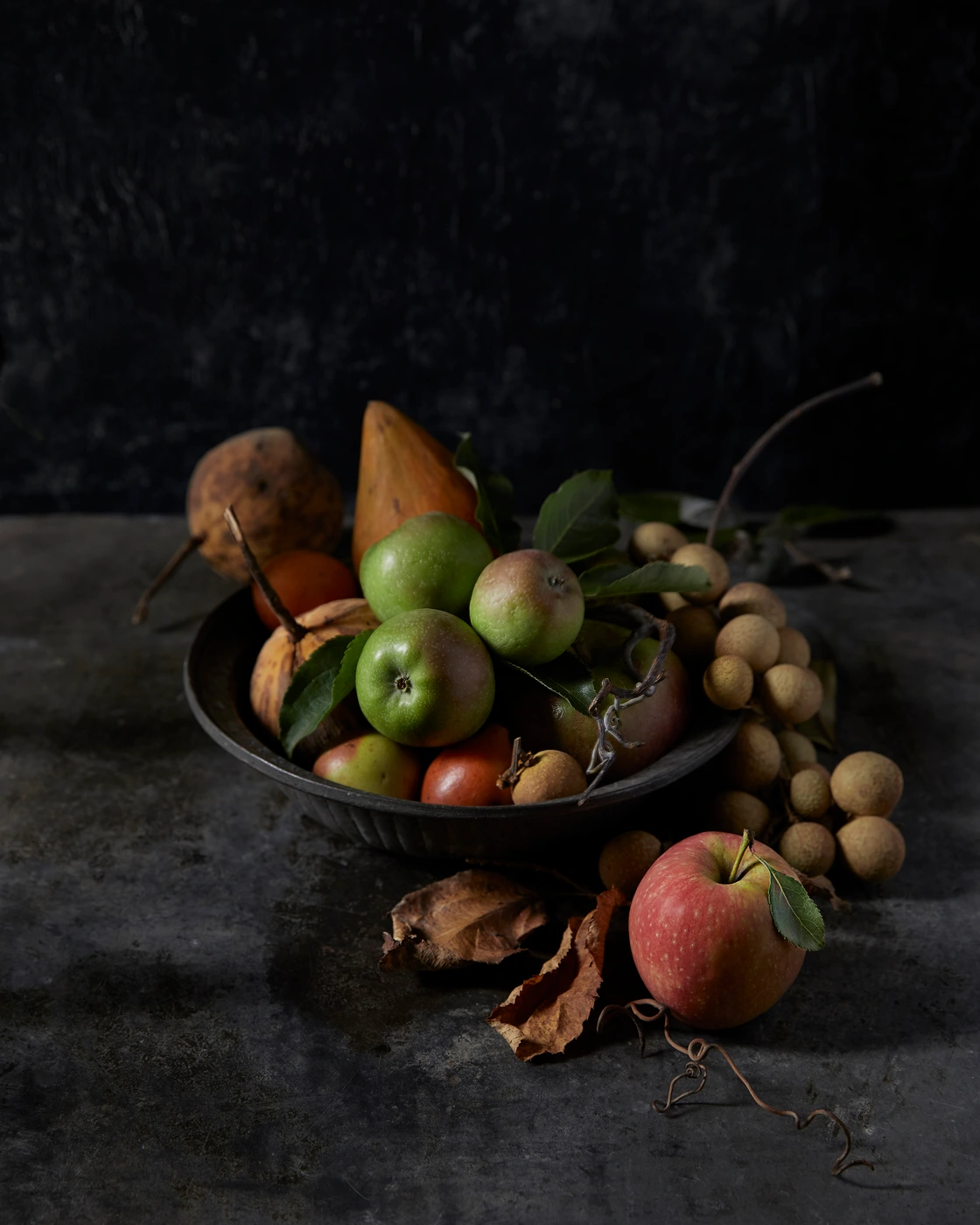 Chiaroscuro still life bowl of fruit with apples and pears on a dark table by Brent Parker Jones