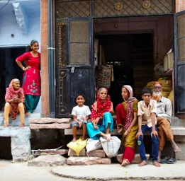 Group of people of varying ages gathered on stone steps outside a residential building in India, photographed by Lou D'Angelo.