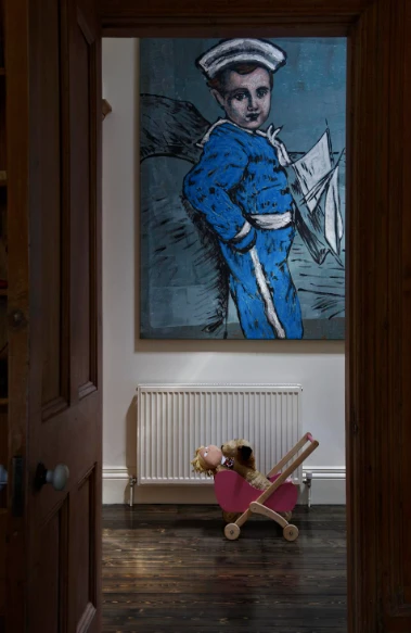 Pink toy pram holding stuffed animals on a dark wooden floor viewed through an open wooden doorway with a large painting above