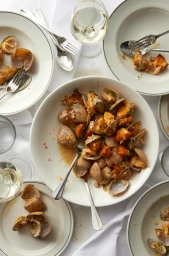 Overhead view of white bowls filled with steamed clams and bread pieces on a white tablecloth, photographed by Earl Carter.