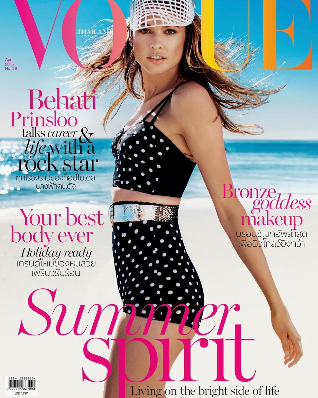 Vogue Thailand cover featuring Behati Prinsloo in a polka-dot bikini and white hat, on a beach with blue sky and ocean backdrop.
