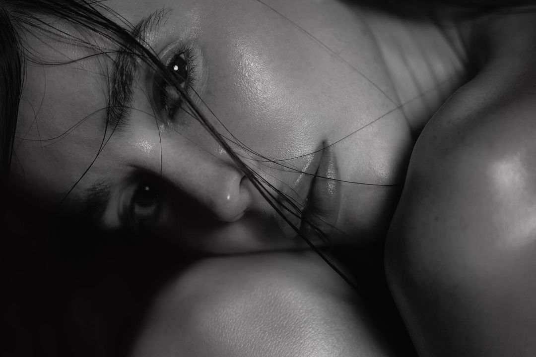 Close-up black and white portrait of a woman resting her head, with strands of hair falling across her face.