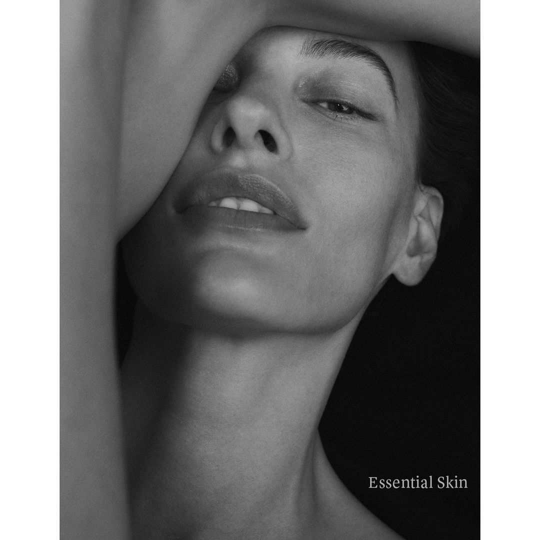 Monochrome close-up portrait of a woman with an arm raised across her forehead, captured by Chris Colls.