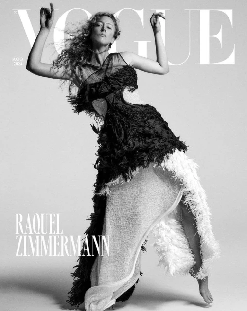 Vogue cover featuring Raquel Zimmermann in a black and white feathered dress, striking a pose with arms raised against a clean background.
