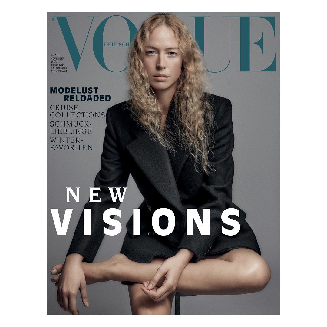 Vogue Deutsch cover featuring a woman with blonde hair in a black blazer sitting against a gray background with large magazine text.