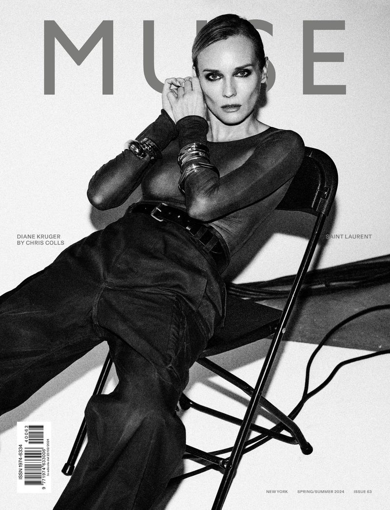 Black and white magazine cover featuring Diane Kruger posing in long sleeves and trousers, sitting on a chair in front of a white wall.