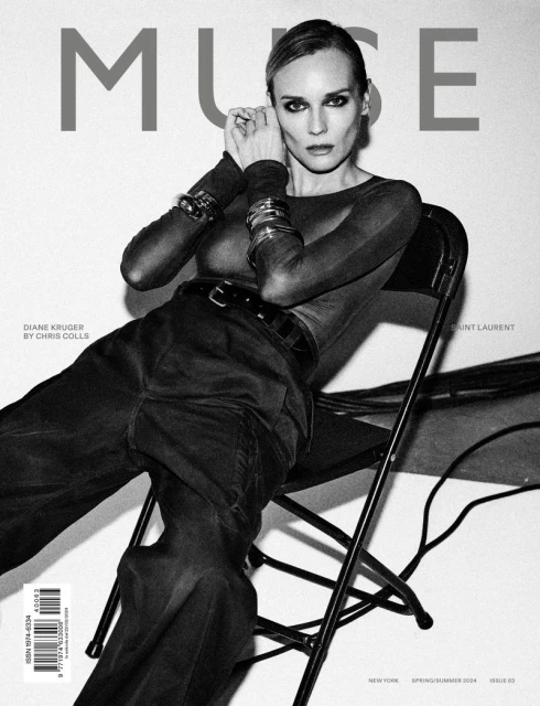 Black and white magazine cover featuring Diane Kruger posing in long sleeves and trousers, sitting on a chair in front of a white wall.