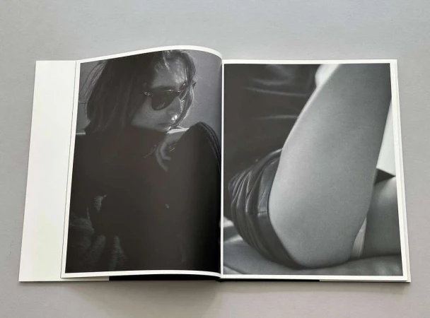 Open photo book on a grey surface displaying black and white portraits by Chris Colls