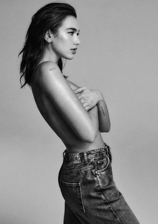Black and white portrait of Dua Lipa in profile wearing denim jeans against a plain studio background.