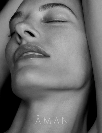 Monochrome close-up portrait of a woman with eyes closed and arms raised against a dark background by photographer Chris Colls.