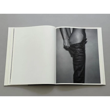 Open book shows a grayscale image of an adult wearing leather pants, viewed at eye-level, in a photo studio setting.