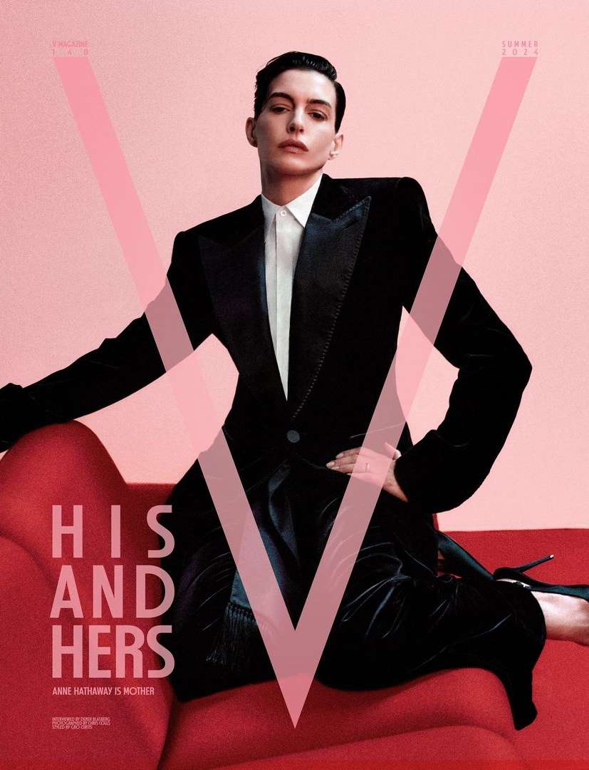 Magazine cover featuring an adult woman with short, dark hair, wearing a black tuxedo and heels, posing on a red chaise lounge against a pink backdrop.