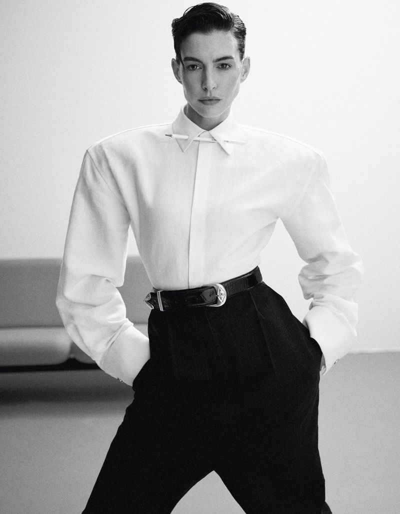 Monochrome portrait of a female model in a white button-down shirt and high-waisted black pants, posing against a neutral backdrop.
