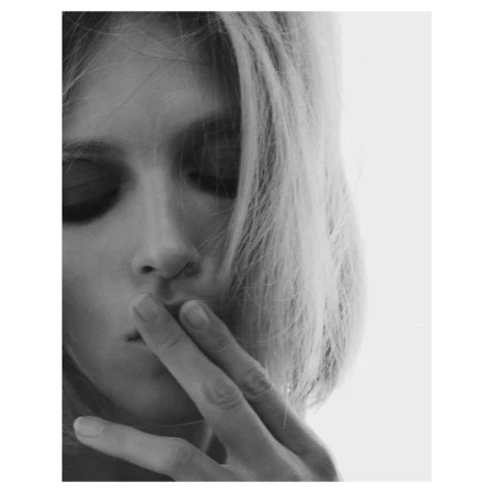 Close up monochrome portrait of a woman with fingers near her mouth against a bright white background