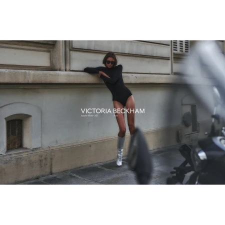 Woman in black bodysuit and silver boots leaning against an exterior stone wall in Paris photographed by Chris Colls