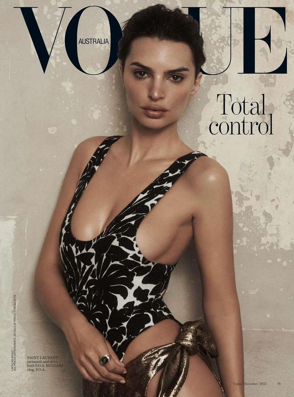 Emily Ratajkowski posing in a black and white patterned swimsuit against a mottled concrete wall for a magazine cover