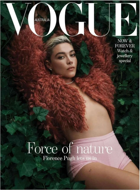 Florence Pugh on Vogue Australia cover. Woman with blonde hair in brown jacket poses with pink shorts among green leaves.