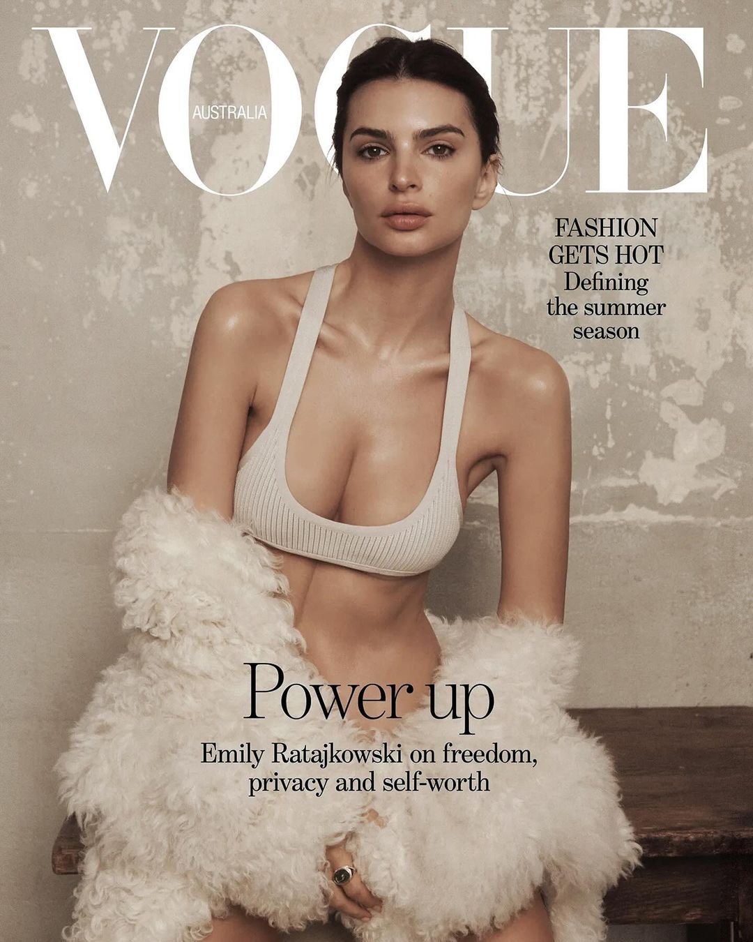 Vogue Australia cover featuring Emily Ratajkowski in a light-colored top and white furry jacket, with a neutral background and magazine text.