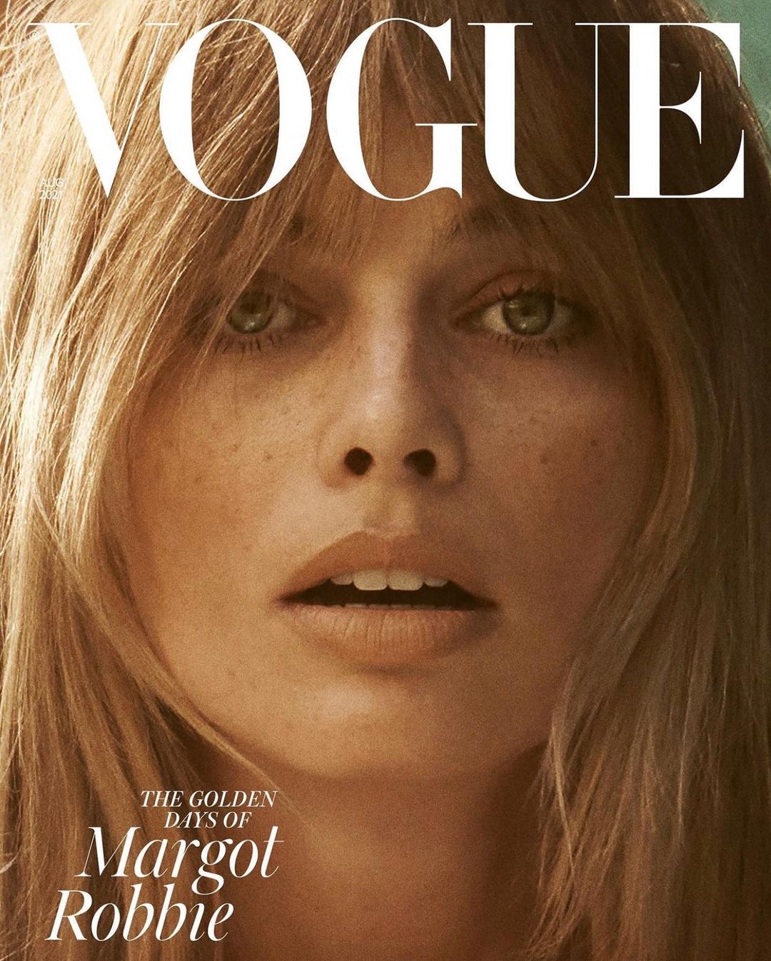 Close-up of a woman with green eyes and freckles with blonde hair on the cover of Vogue magazine with the text "The Golden Days of Margot Robbie."