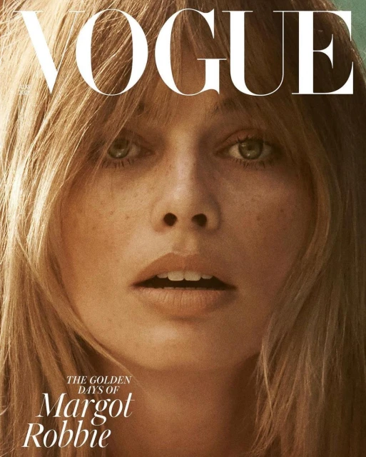 Close-up of a woman with green eyes and freckles with blonde hair on the cover of Vogue magazine with the text "The Golden Days of Margot Robbie."