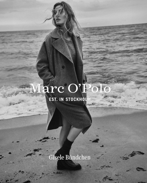 A woman in a coat stands on a beach in a black and white fashion photograph for Marc O'Polo, promoting their Stockholm line.