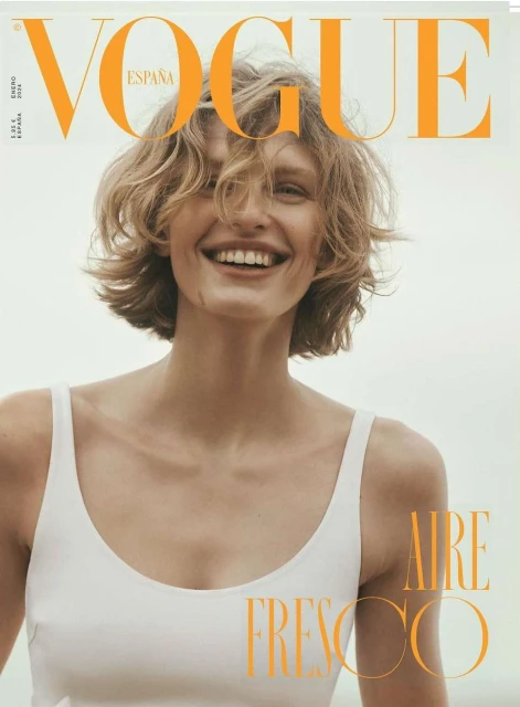 Vogue Espana cover featuring a smiling woman with short blonde hair wearing a white top, set against a bright background.