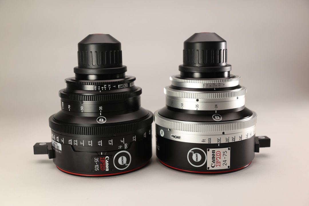 Two Canon FD lenses, one black 35-105mm and one silver 24-75mm, are arranged side by side on a plain background in a studio shot.