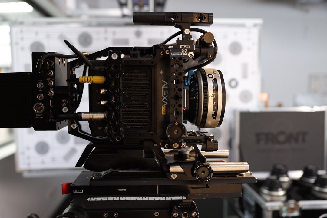 Professional cinema camera on a tripod in a studio setting, with detailed focus on the lens and camera body, showcasing filming equipment.
