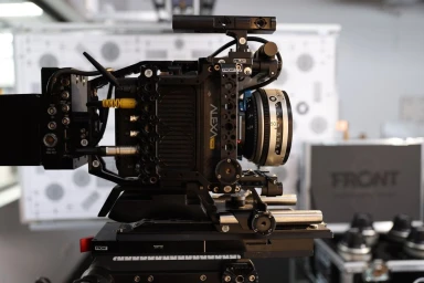 Professional cinema camera rig in profile view featuring an Arri Alexa Mini LF body mounted in a black metal cage with a prime lens.