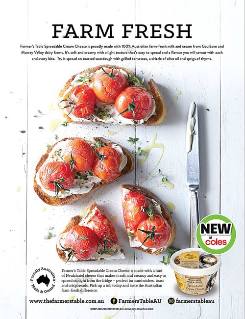 Toasted sourdough bread topped with cream cheese and roasted tomatoes, drizzled with olive oil and thyme, beside cheese container.