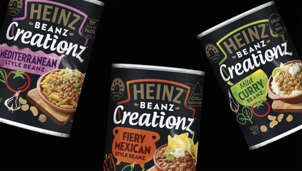 Three cans of Heinz Beanz Creationz featuring Mediterranean, Fiery Mexican, and Mild Curry styles, food photography on black backdrop.