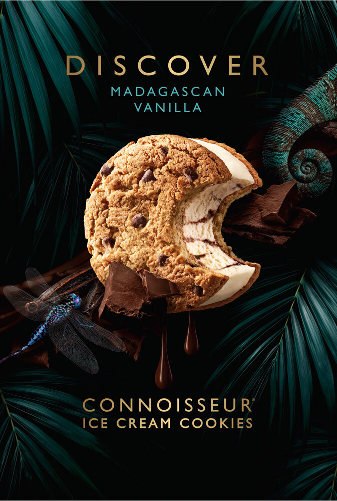 Close-up of a Connoisseur ice cream cookie with a bite taken out of it, chocolate sauce, palm leaves, chameleon, and a dragonfly.