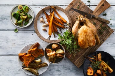 Overhead food styling shot of roasted whole chicken with glazed carrots and brussels sprouts styled by Lisa La Barbera