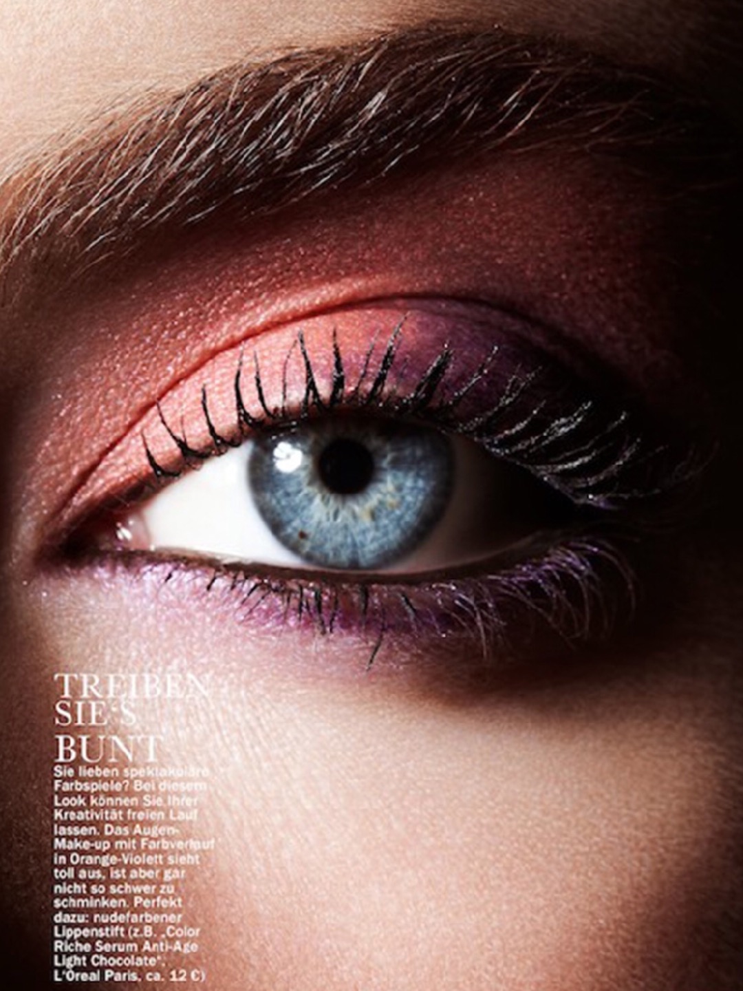 Close-up of a woman's eye with orange, violet, and brown eyeshadow and eyebrow. The skin is visible on her face near her eye.