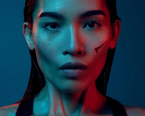 Close-up portrait of a young Asian woman with wet hair and water droplets on her face, dramatically lit with red and blue lighting.