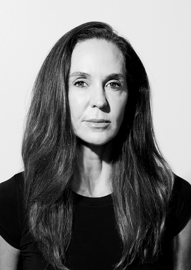 Black and white portrait of an adult female with long brown hair and a black t-shirt against a bright white background.