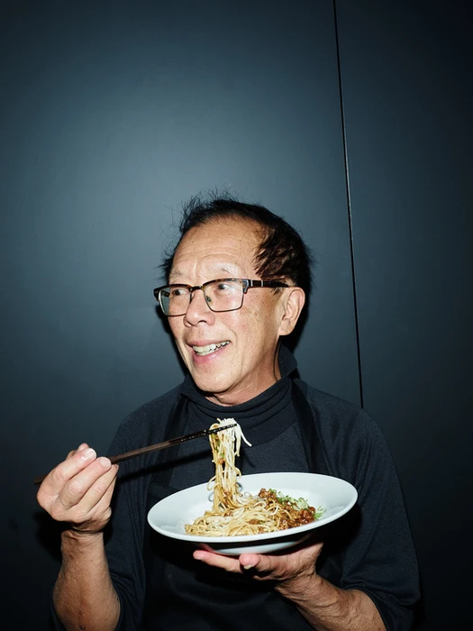 An older man wearing glasses and a black turtleneck eating noodles with chopsticks in Melbourne, captured by Kristoffer Paulsen.
