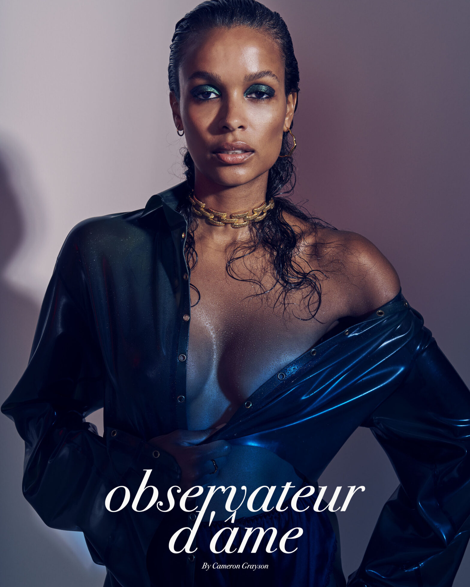 A dark-skinned female model poses in a shiny, wet-look shirt and gold choker against a soft pink-to-purple gradient background.