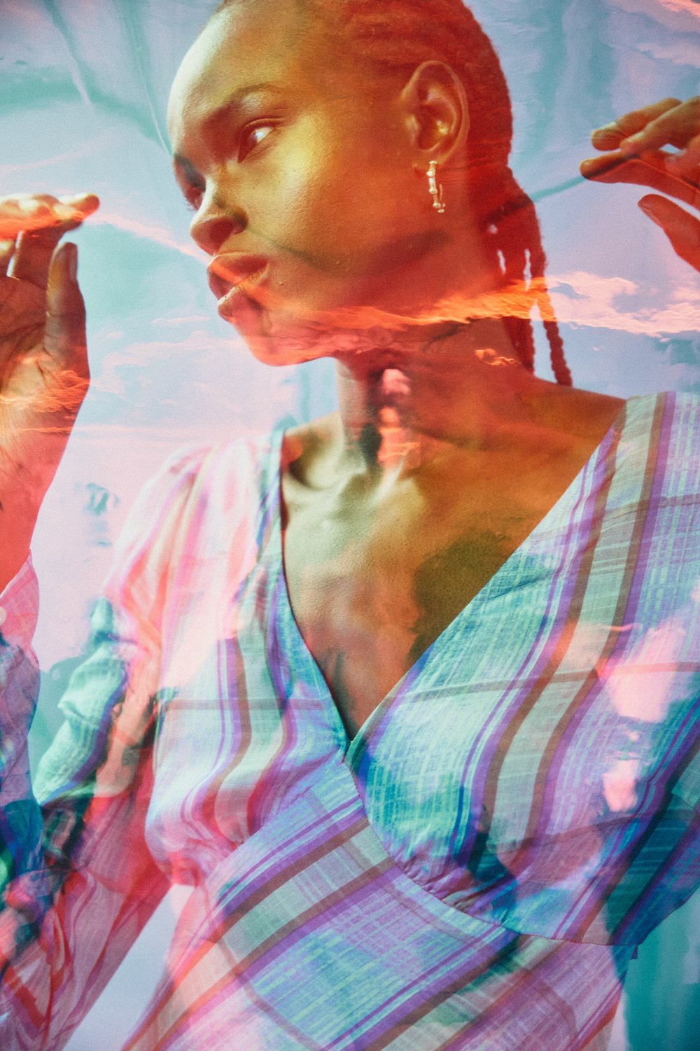 Portrait of a woman with a striped top with a blue sky and clouds superimposed on her image, creating a dreamy, ethereal aesthetic.