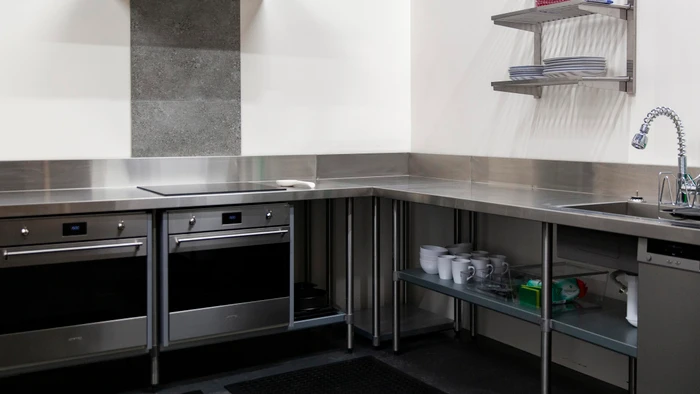 Commercial stainless steel kitchen interior with built-in ovens and shelving units