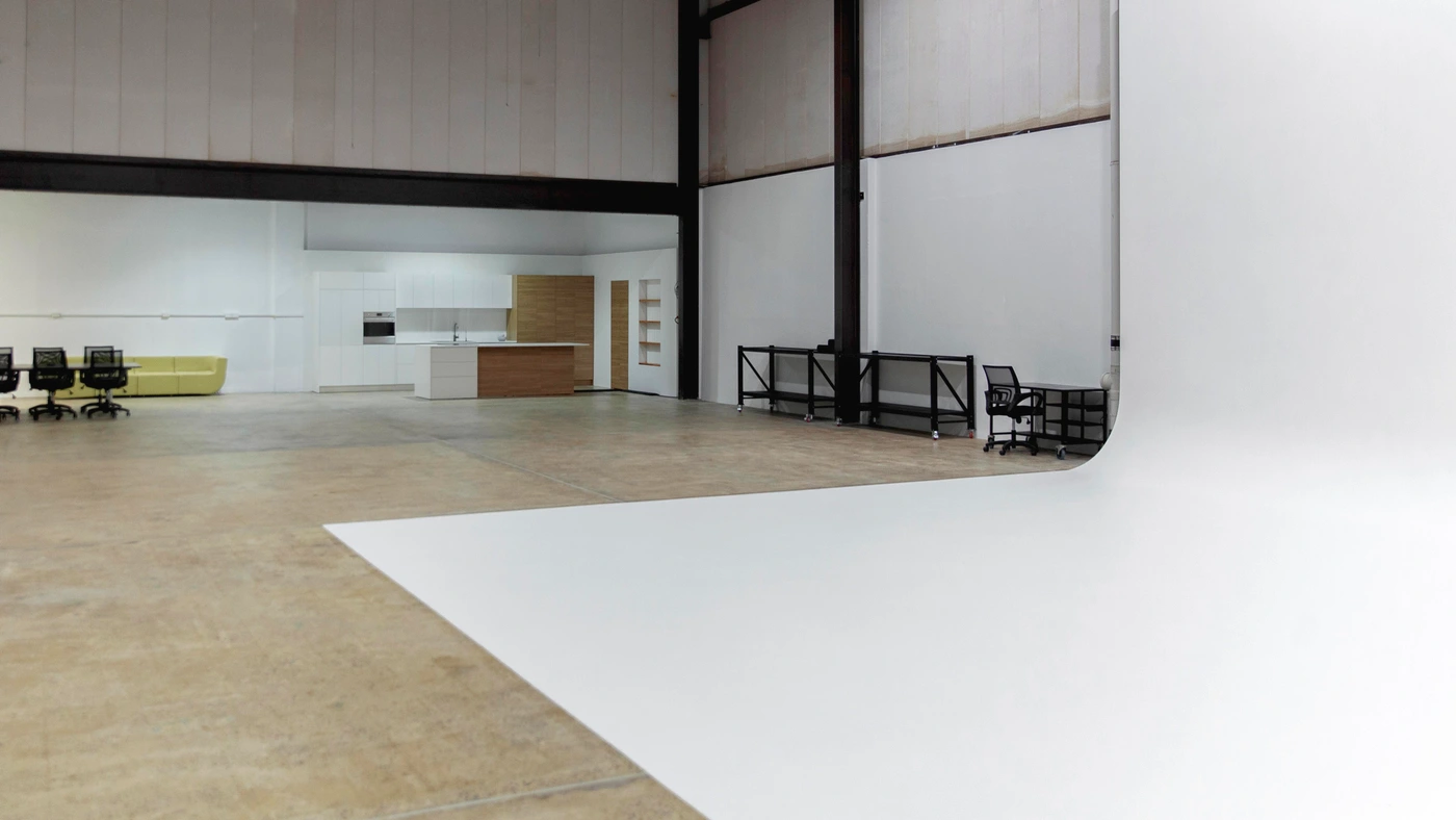 Spacious industrial photo studio interior with a large white cyclorama sweep and a polished concrete floor.