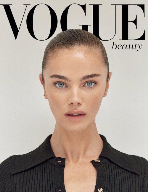 Close-up of a model on the cover of Vogue Beauty magazine, featuring her face, black ribbed top, and minimal off-white background.