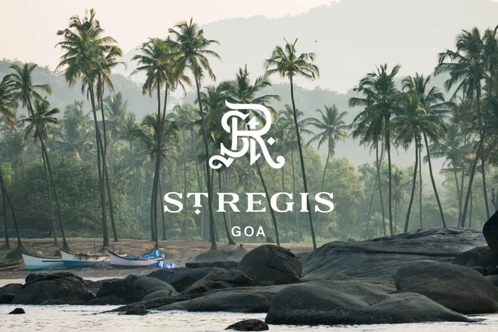 St. Regis Goa branding overlay featuring palm trees, rocky coastline, and small boats on a misty morning.
