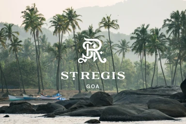 St. Regis Goa branding overlay featuring palm trees, rocky coastline, and small boats on a misty morning.