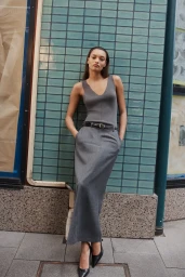 Model in grey tank top and long grey skirt leaning against a turquoise tiled wall in Sydney by Emil Vrisakis