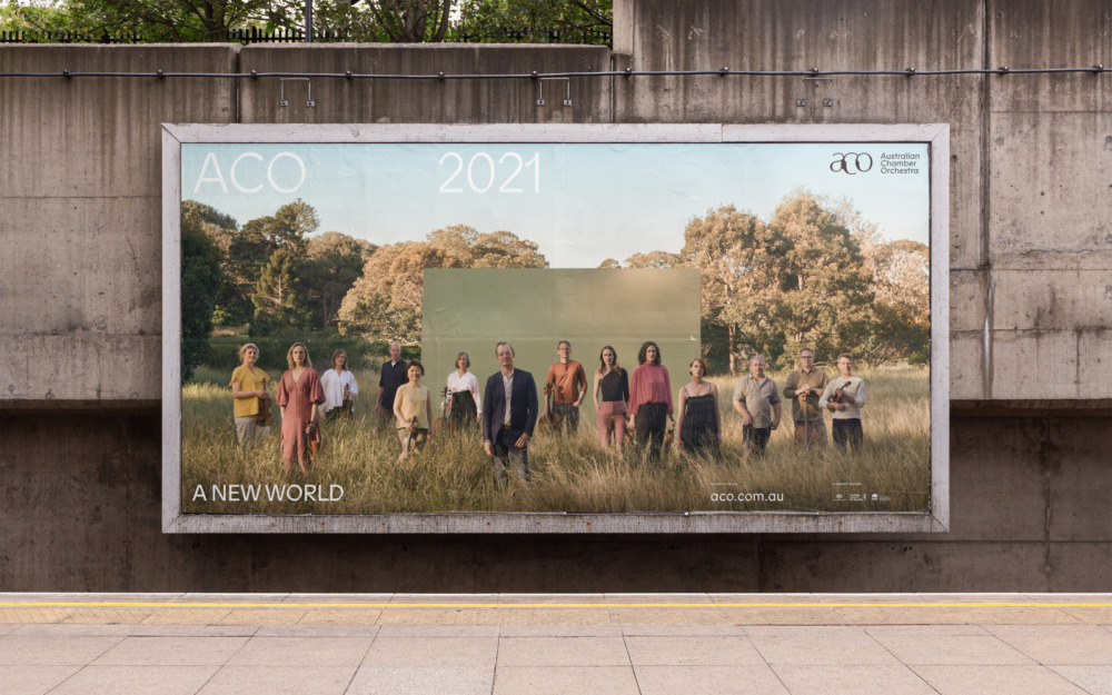 Outdoor billboard advertisement featuring a group of people in a field with trees in the background, promoting Australian Chamber Orchestra.